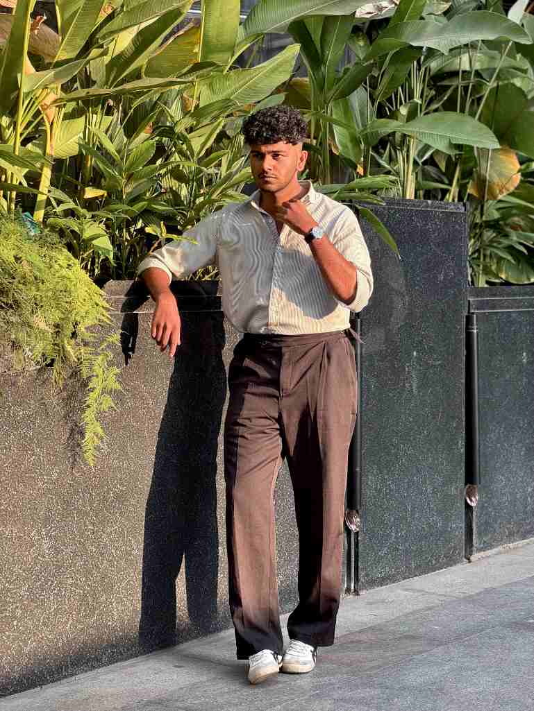 Best Digital Marketing Strategist in Kerala standing beside lush tropical plants and a modern black wall in warm golden sunlight.